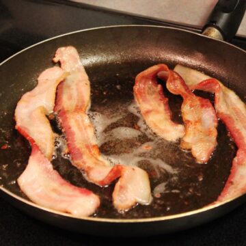 American style bacon cooking in a pan